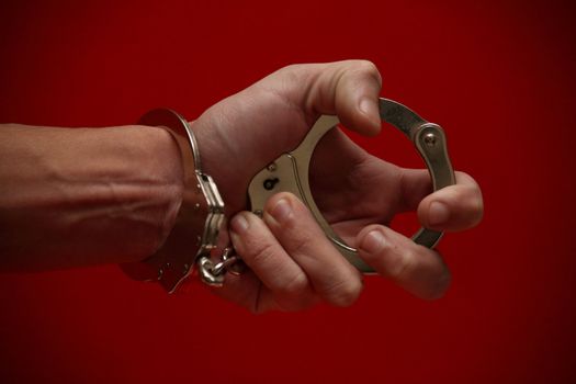 A really expressive photograph of a hand (handcuffed) holding the other end of the cuffs, on a red background! :)