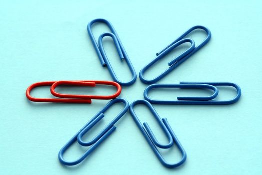 One red paper clips among blue others