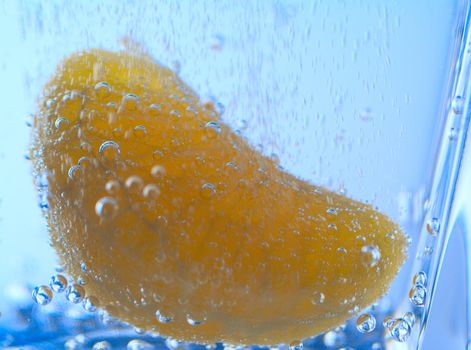 close-up slice of tangerine in water with bubbles