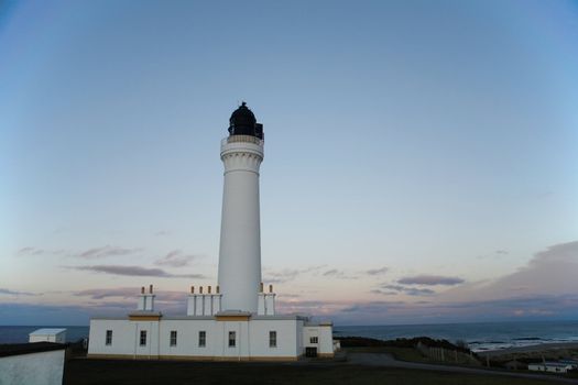A white lighthouse with the sea in the background.