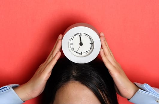 A businesswoman holding a clock, can be used for time or deadline concept