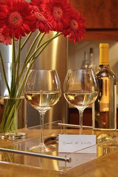 Glasses of white wine with gerbera daisies on counter in the kitchen