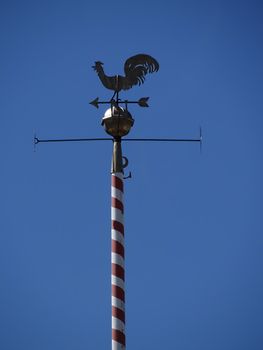Closeup of antique weather cock in front of blue sky