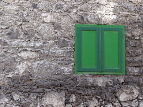 Green window shutter on a stone wall