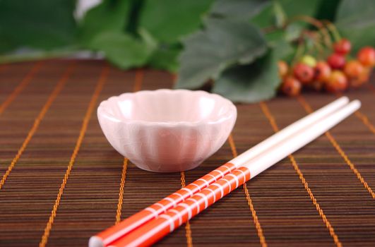 Cup and chopsticks on a wooden napkin against plants