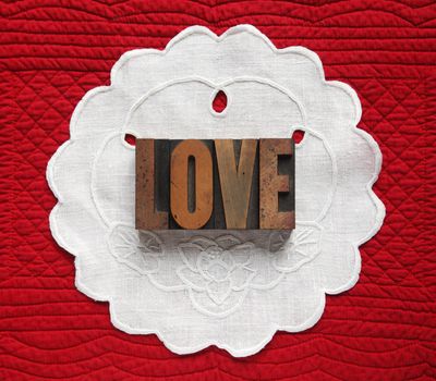the word 'love' on scalloped linen on a red quilted background
