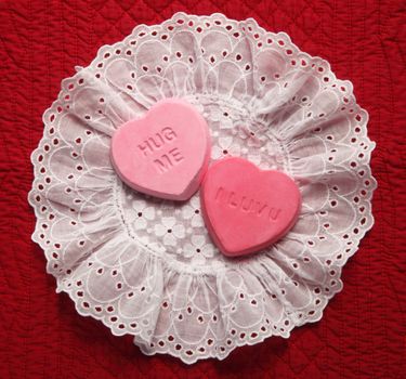 two heart candy replicas on an eyelet doily