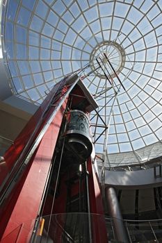 Huge hall of modern shopping centre with the glass lift and a transparent glass dome