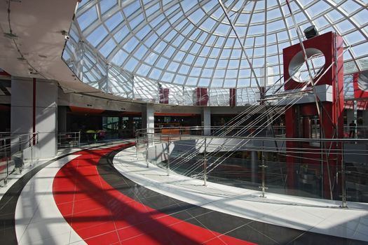 Huge hall of modern shopping centre with the glass lift and a transparent glass dome