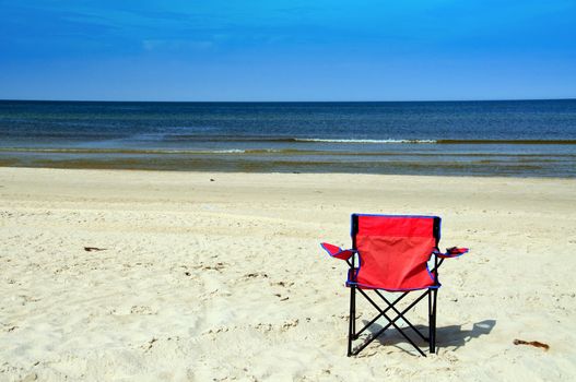 A red beach chair facing the sea