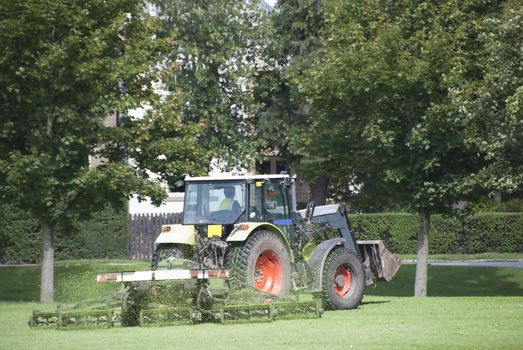 A Tractor Mowing Grass in a Park