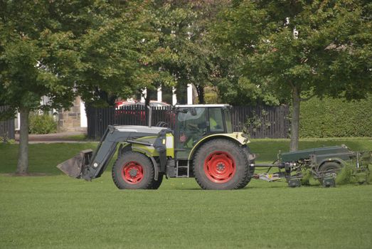 A Tractor Mowing Grass in a Park