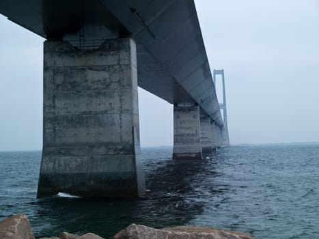 Under a massive modern design concrete bridge support over water