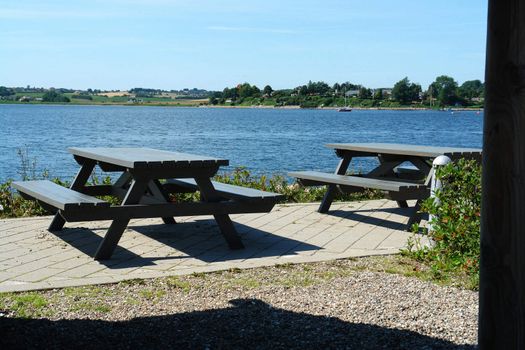 Attractive wooden picnic tables seating by the sea ocean with great landscape