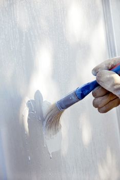 painting wooden door in white color by blue brush