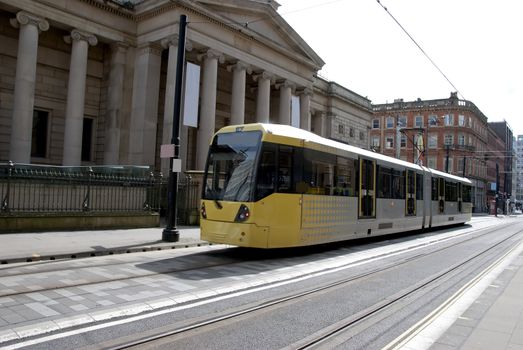 A Modern Yellow Tramcar passing an old Art Gallery in a city street