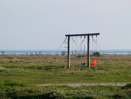 Cute playground with colorful swings on the beach by the ocean