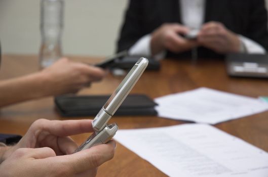 Business team check their phones during a meeting.