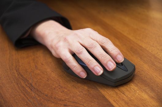 Woman's hand using a wireless computer mouse. Focus is on the front of the mouse / end of the fingers.
