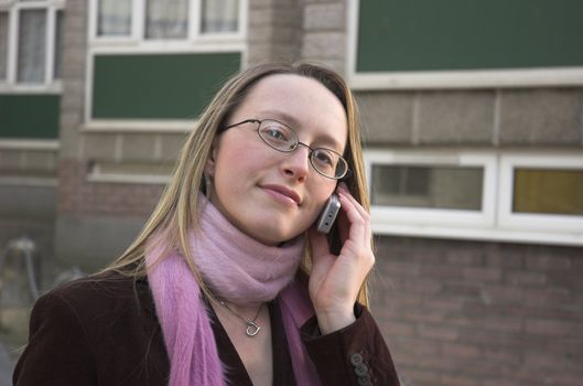 Young female student using her mobile phone outside student accomodation building.