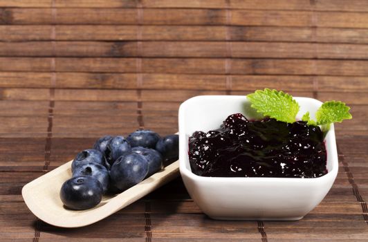 blueberry jam and blueberries on a shovel on wooden background