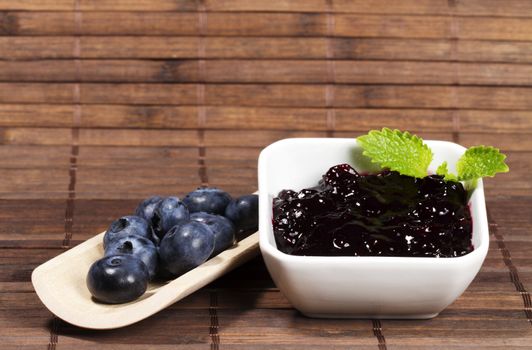 blueberry jam and blueberries on a shovel on wooden background