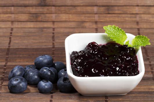 blueberry jam and blueberries aside on wooden background