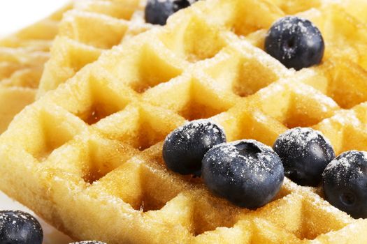 closeup from waffels with sugar covered blueberries and syrup