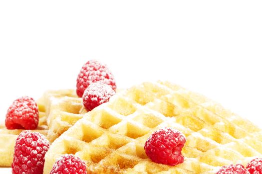 sugar covered raspberries on waffles with syrup on white background