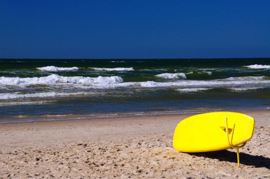 A yellow rescue surf board on the beach