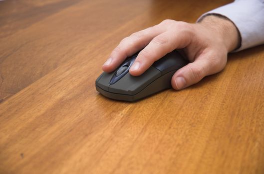 Man's hand using a wireless computer mouse on a boardroom table