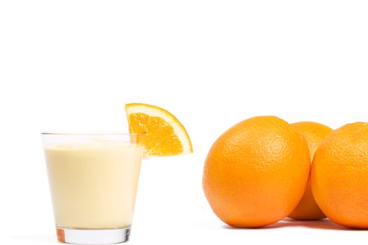 piece of a orange on a orange milkshake in front of oranges on white background