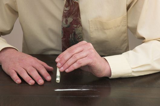 Man preparing to snort a line of cocaine with a rolled up bank note.