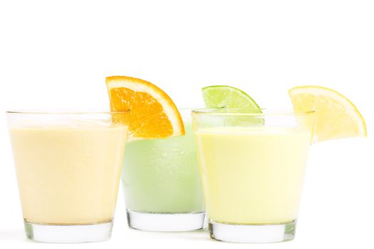 three cold citrus fruit milkshakes on white background