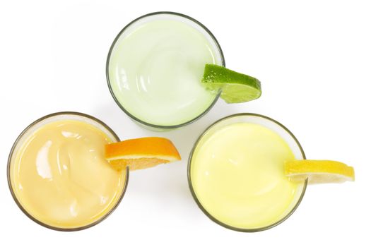three cold citrus fruit milkshakes from top on white background