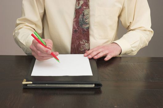 Man working at desk with pens held like chopsticks