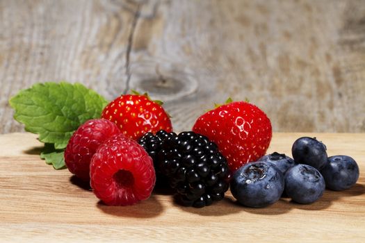 wild berries on a chopping board on wooden background