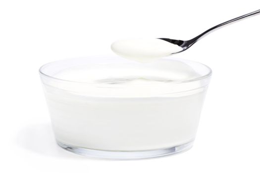 yogurt on a spoon over yogurt in a glass bowl on white background