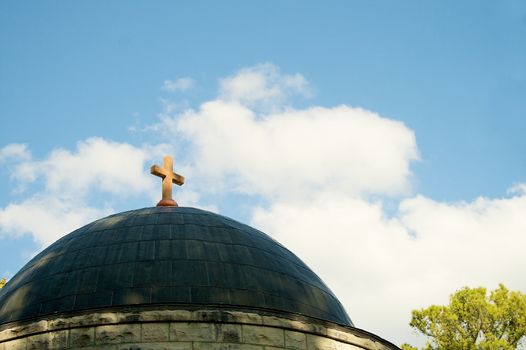 A rusted cross is pervhed atop a church dome