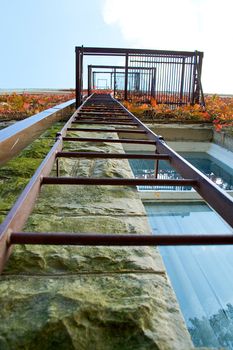 An old style fire escape from straight below, with red ivy