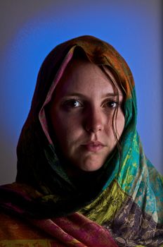 A sad looking girl in a brightly colored shawl 