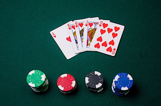 A royal flush is laid out with poker chips on green felt