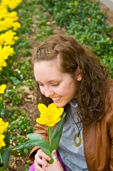 a pretty young girl smells an early spring flower