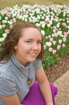 A pretty young girl poses in front of early spring flowers