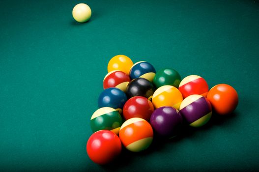 Billiard balls are racked in a triangle, waiting to be broken by the cue ball. Shallow depth of field.