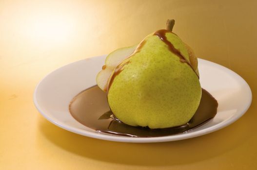 A sliced pear with chocolate sauce on a white plate