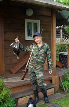 Smiling hunter with a shotgun in his hand grouse.
