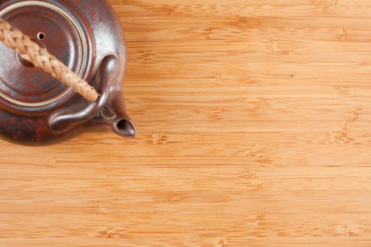 Tea Pot and Bamboo Textured Surface Background with Plenty of Room for Text. Focus is on the Bamboo Surface.