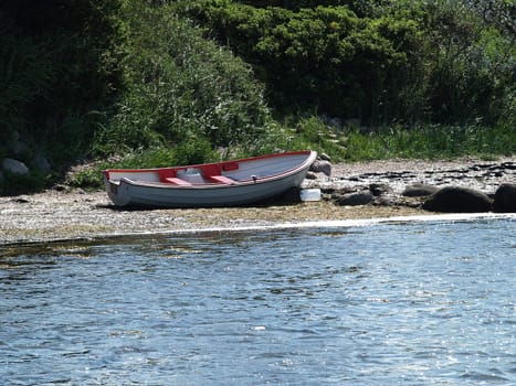 Small classical wooden fishing boat dory rowboat on the sea shore beach