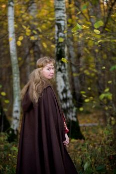 The blonde girl in medieval dress in the autumn forest
